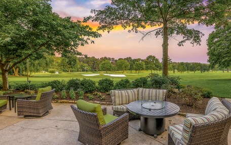 An outdoor patio area with wicker furniture and a view of a golf course.