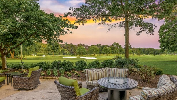 An outdoor patio area with wicker furniture and a view of a golf course. - Turf Valley Resort (Ellicott City)