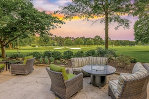An outdoor patio area with wicker furniture and a view of a golf course.