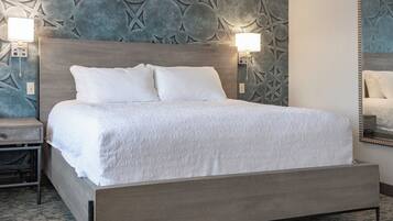 Una habitación de hotel moderna con una cama grande, dos lámparas de noche y un panel decorativo en la pared.