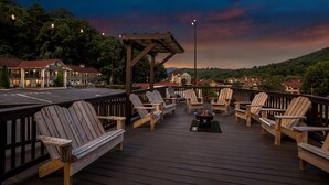 A deck with Adirondack chairs and a fire pit, overlooking a town with buildings and a forested hill. - Quality Inn (Helen)