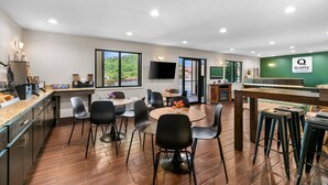 A hotel room with a dining area, a kitchen, and a large window offering a view of greenery. - Quality Inn (Helen)