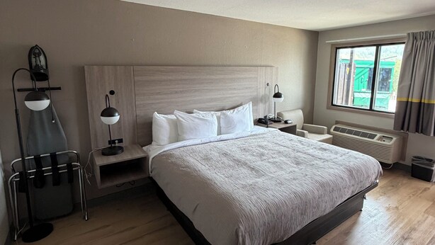 A modern hotel room with a large bed, bedside tables, a desk, a lamp, and a window with curtains. - Quality Inn (Helen)