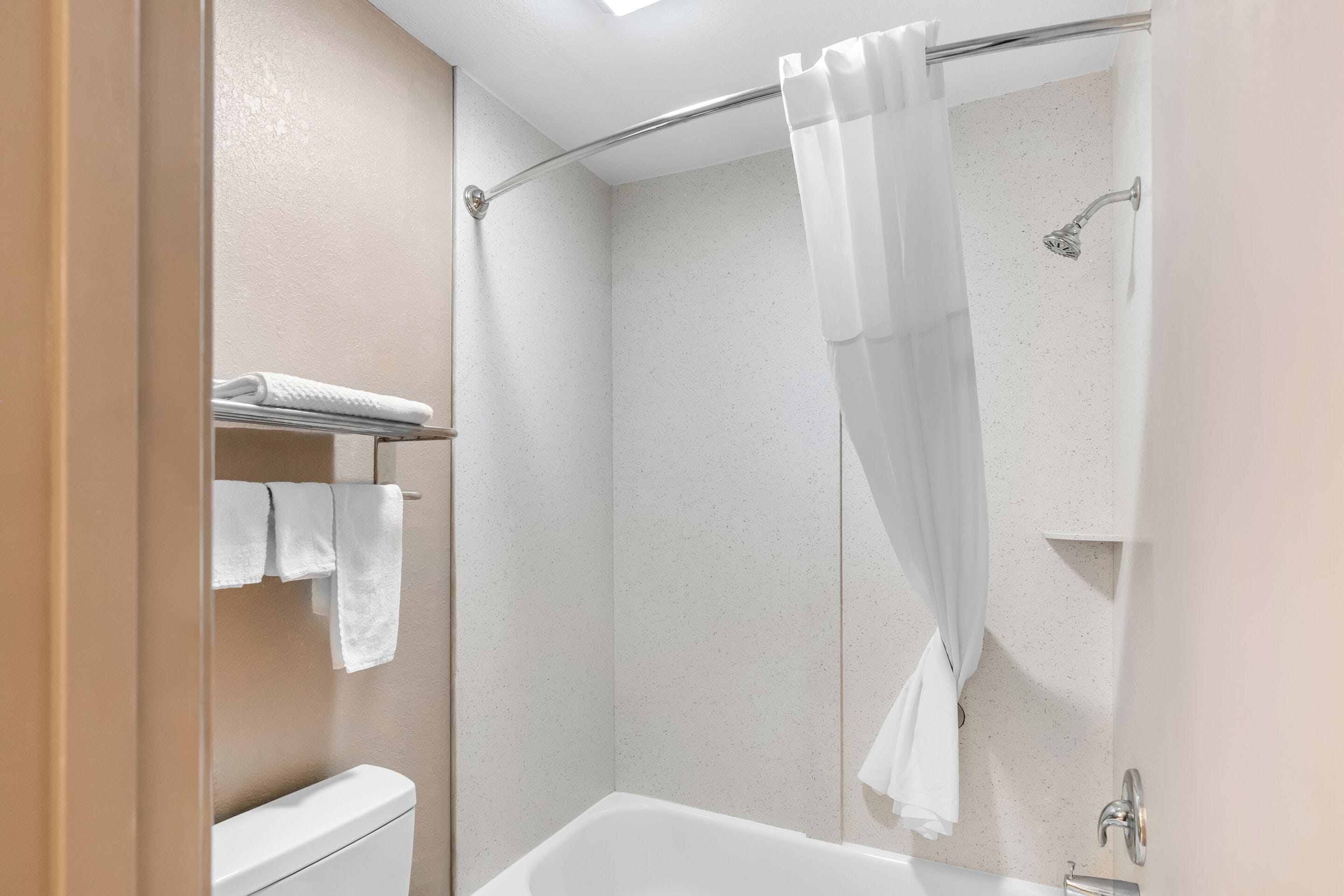 A modern bathroom with a shower, toilet, and towel rack.