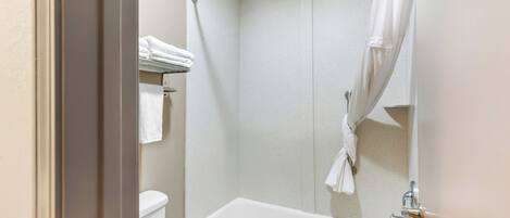 A bathroom with a bathtub, toilet, and a shower area.