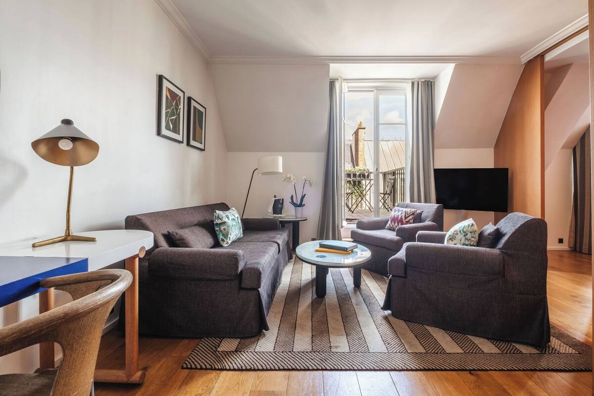 A modern living room with a sofa set, a coffee table, a desk with a lamp, and a TV.