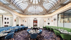 Une salle à manger spacieuse avec de hauts plafonds, un décor orné et un arrangement floral central.