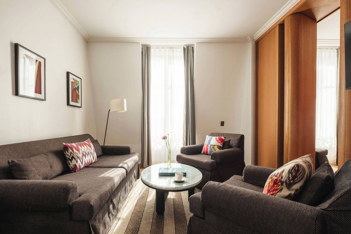 A living room with a sofa, armchairs, a coffee table, and a TV.
