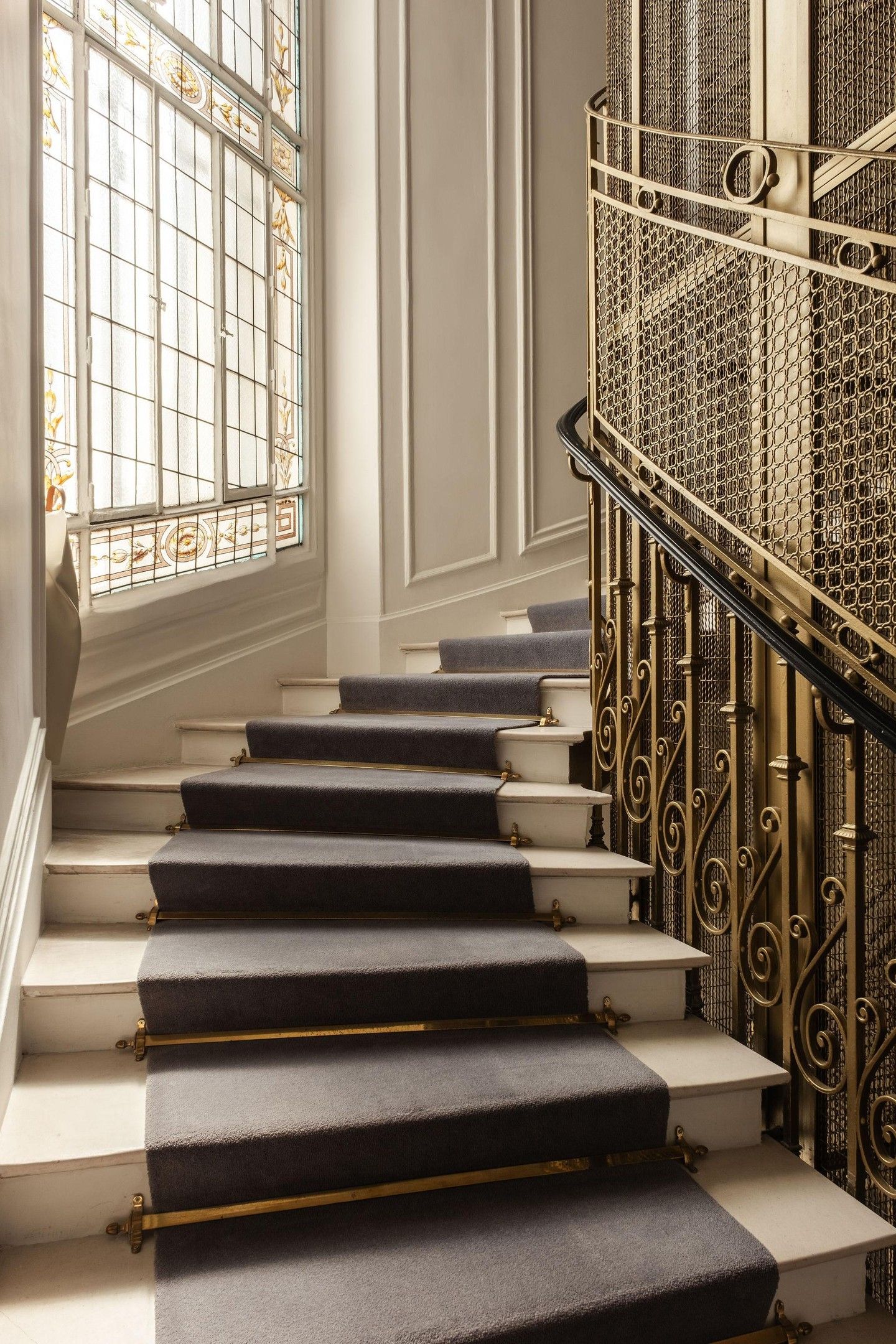 A staircase with dark carpeted steps and ornate metal railings.