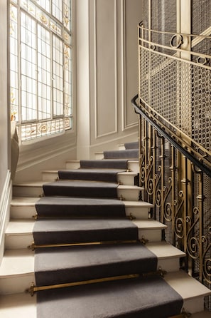 A staircase with dark carpeted steps and ornate metal railings. - Hotel Vernet (Paris)