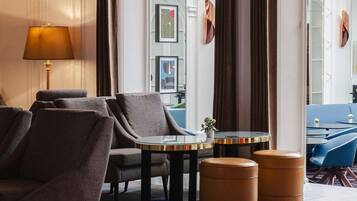 Une chambre d’hôtel avec un canapé, des fauteuils, une petite table et un tapis coloré.