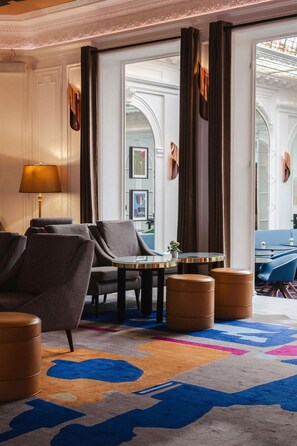 A hotel room with a sofa, armchairs, a small table, and a colorful rug. - Hotel Vernet (Paris)