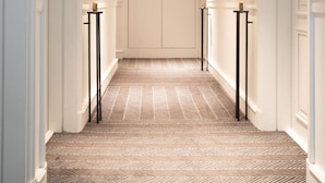 Un couloir avec un tapis à motifs, des murs blancs et des portes de chaque côté.