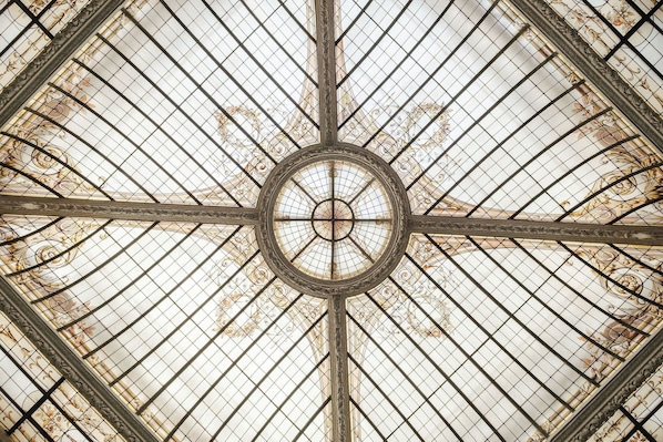 A ceiling with a central circular design and radiating lines. - Hotel Vernet (Paris)