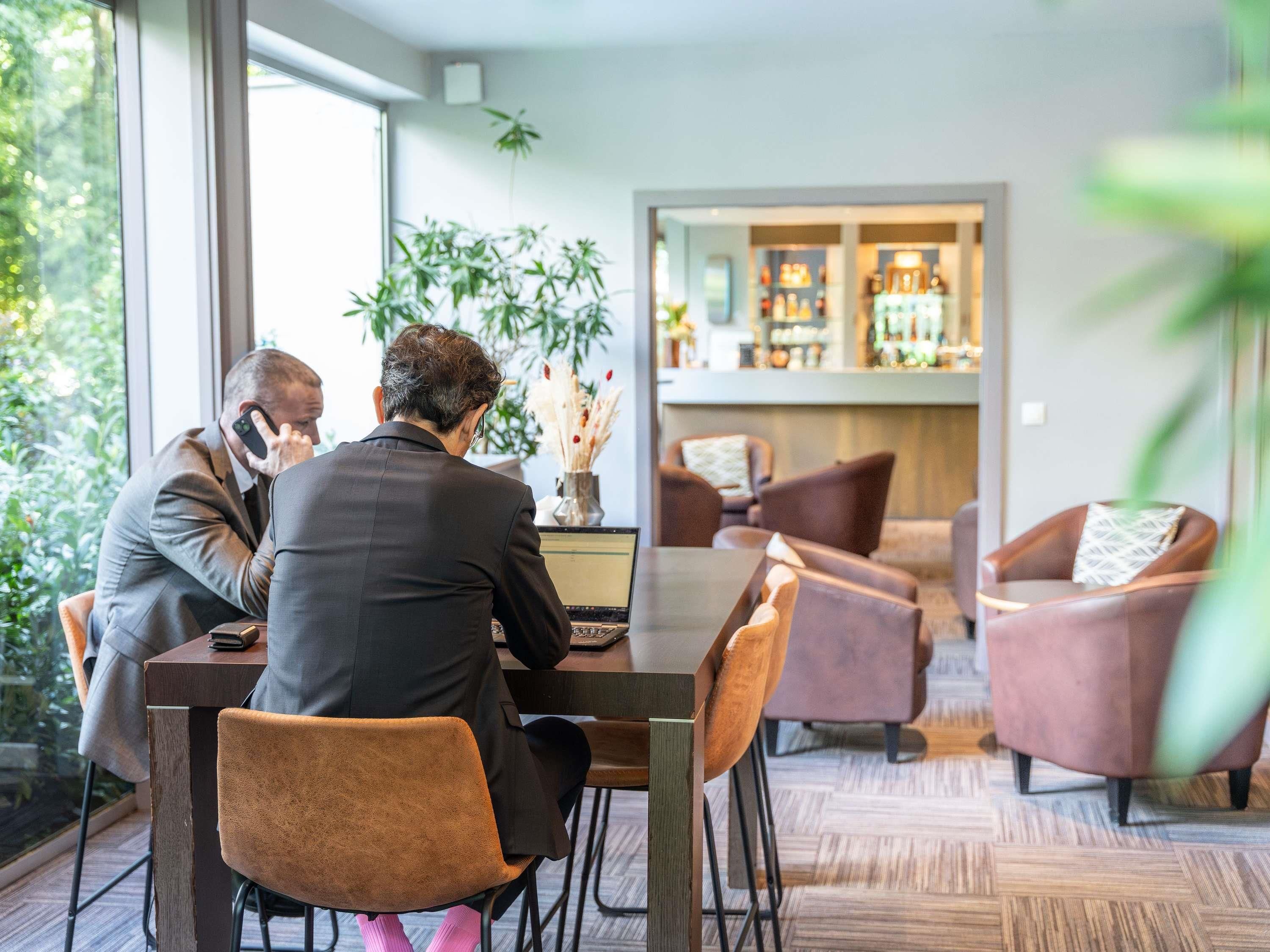 Une salle de réunion moderne, dotée d’une grande table, de chaises confortables et offrant une vue sur un espace bar.