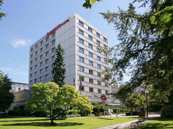 Welcome to Mercure Hotel, featuring a symmetrical facade with a well-manicured lawn and inviting outdoor space.