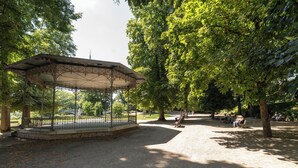 Un jardín con un pabellón, un área pavimentada y bancos.