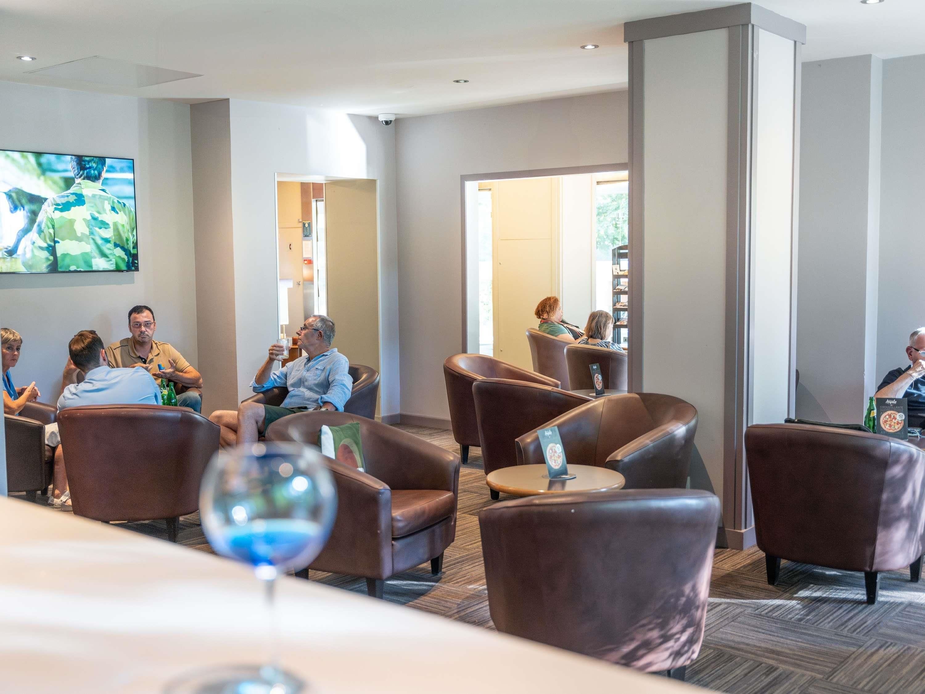 Un espace lounge moderne avec des sièges en cuir, un téléviseur à écran plat et un présentoir à menus.