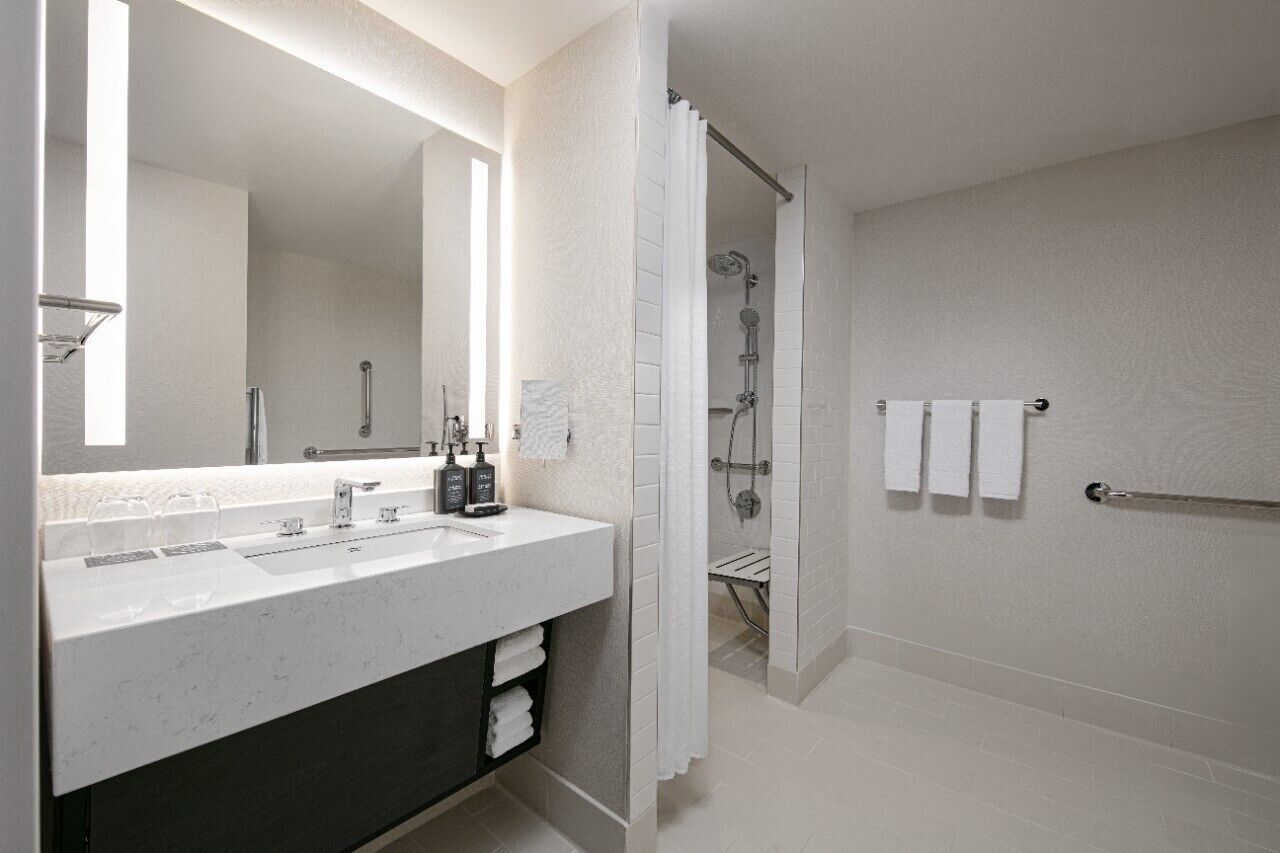 Un baño moderno con un espejo grande, lavamanos doble y zona de ducha.