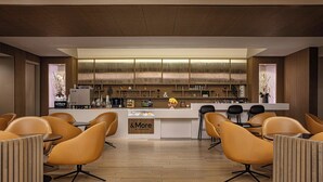 A modern hotel lobby with a central bar area, seating arrangements, and a wooden floor. - Sheraton LaGuardia East Hotel (Flushing)