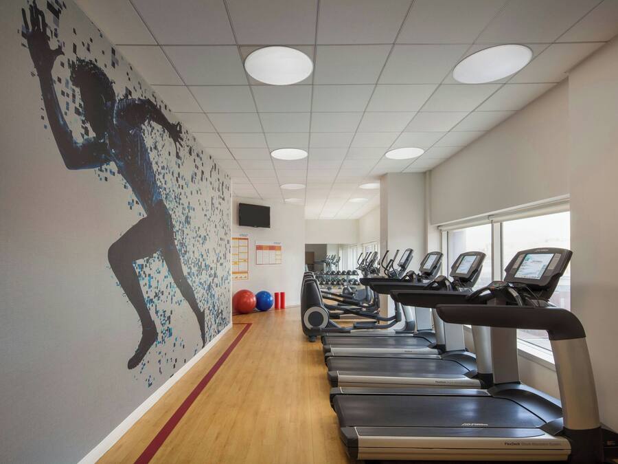 Un gimnasio con cintas de correr, pelotas de ejercicios y un mural en la pared.