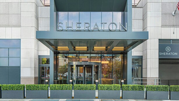 A Sheraton hotel entrance with a modern design, glass doors, and a sign above the entrance. - Sheraton LaGuardia East Hotel (Flushing)