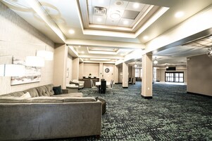 Un hall de hotel espacioso con una amplia zona de estar, un mostrador de recepción y un reloj en la pared.