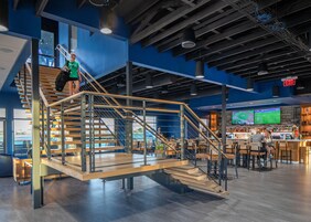 Un interior moderno con una escalera, una zona de estar y un bar.