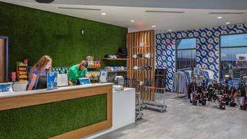 Una recepción con pared verde y mostrador de madera, una tienda de equipo de golf y una pared con diseño.