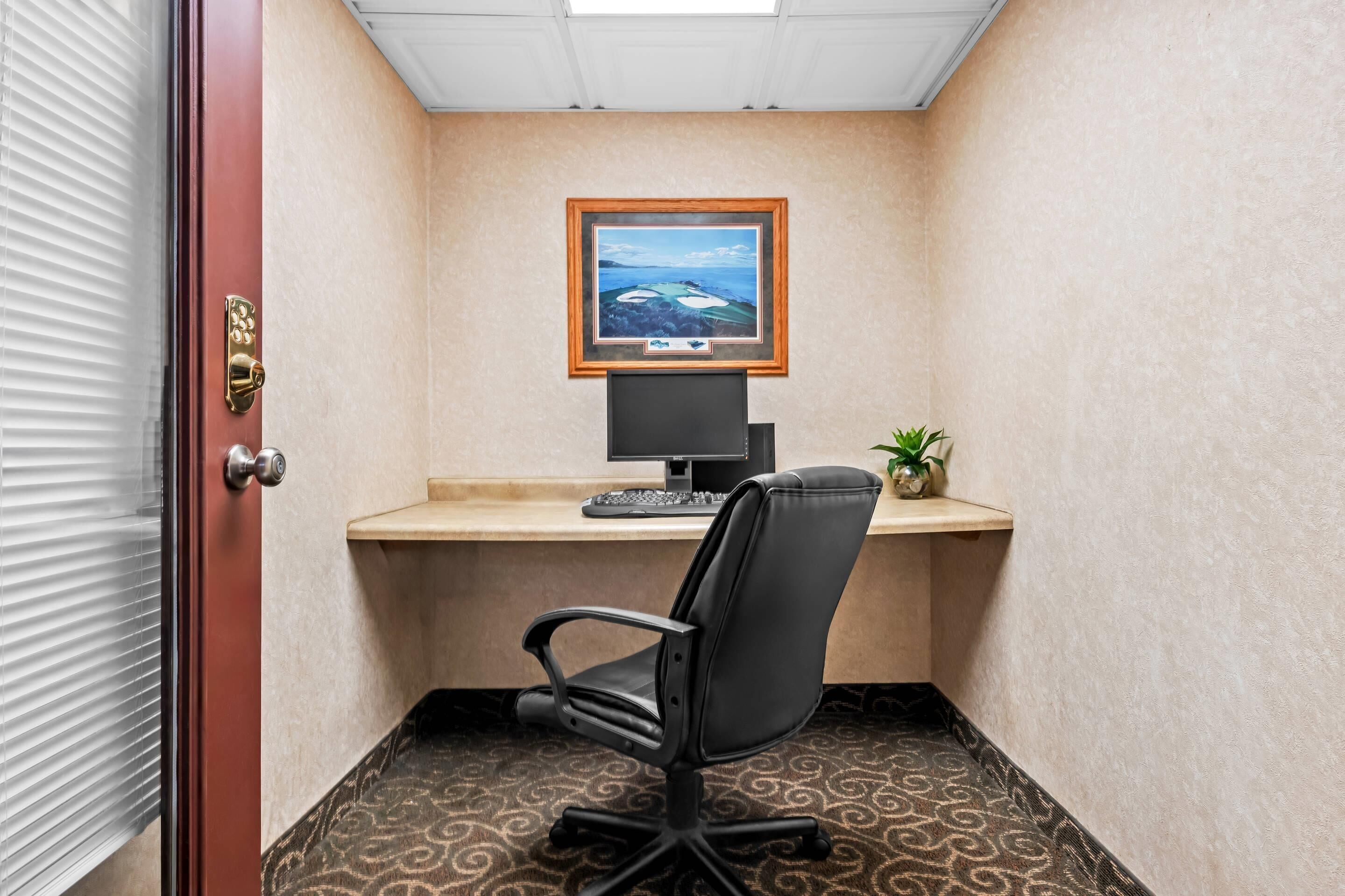 A small office with a desk, computer, and chair.