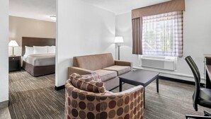 Ein Hotelzimmer mit Bett, einer Couch, einem Sessel, einem Tisch und einem Fenster mit Vorhängen.