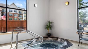 Ein Whirlpool mit Metallleiter, einem Blumentopf und Blick auf ein Gebäude mit einer amerikanischen Flagge.
