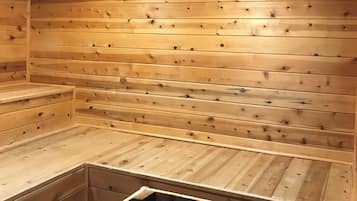 A wooden sauna with benches and a metal grate.