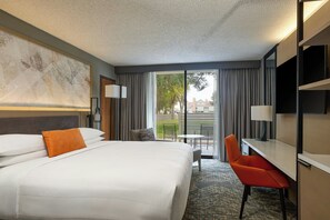 A hotel room with a large bed, a desk, a chair, a TV, and a balcony with a view of the outside. - Marriott El Paso (El Paso)