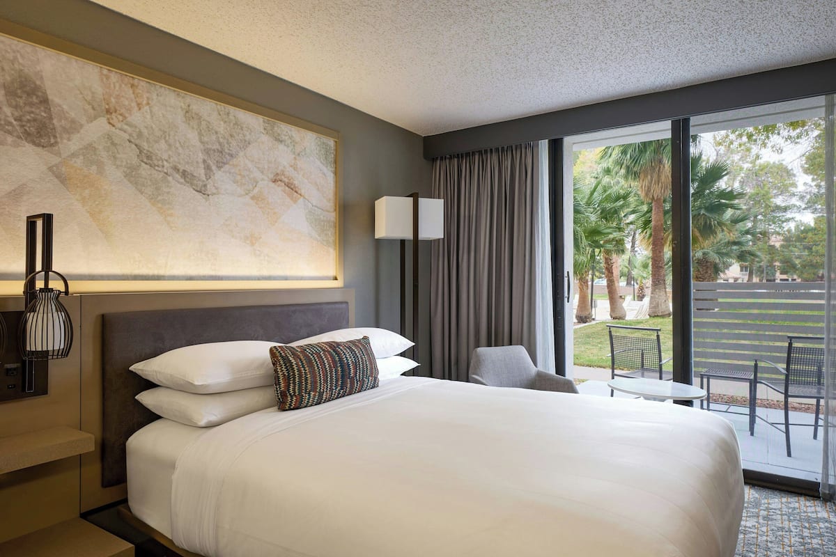 Une chambre d’hôtel avec un grand lit, un bureau, une chaise, une lampe et une vue sur l’extérieur.
