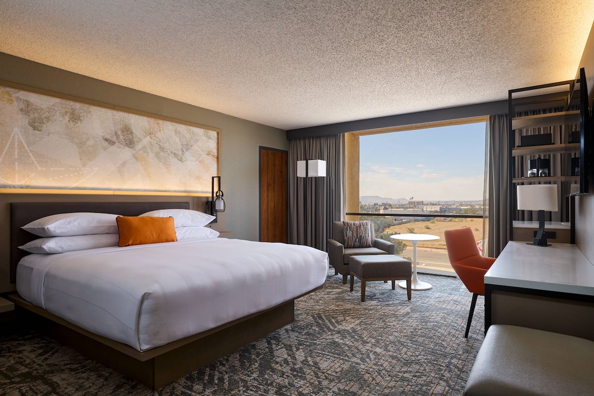 Une chambre d’hôtel avec un grand lit, un bureau, une chaise et une vue sur la ville.