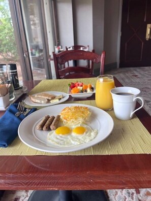 A breakfast table with eggs, sausages, hash browns, and a fruit bowl. - Marriott El Paso (El Paso)