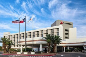 A Marriott hotel with a modern facade, flagpoles, and palm trees. - Marriott El Paso (El Paso)