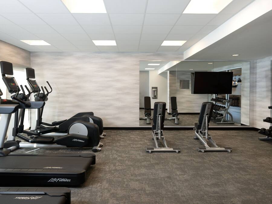 A gym with treadmills, weight machines, and dumbbells.