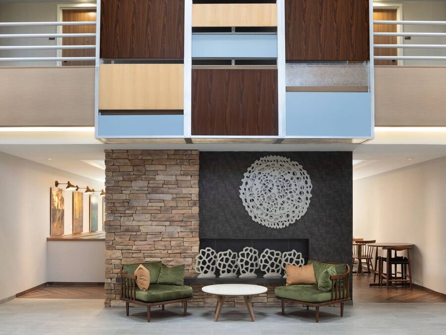 A modern living room with a stone fireplace, two green sofas, and a white coffee table.