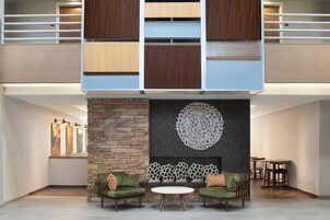 A modern living room with a stone fireplace, two green sofas, and a white coffee table.