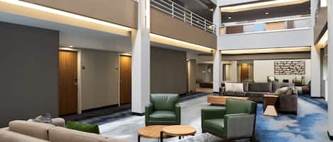 Um hall amplo com várias áreas de estar, teto alto e design moderno.