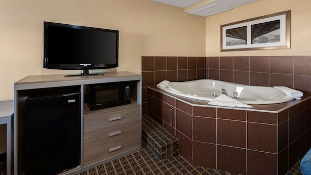 A modern bathroom with a flat-screen TV, a built-in microwave, a large bathtub, and a tiled floor. - Best Western Adena Inn (Chillicothe)