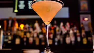 A martini glass on a bar counter with a blurred background of bottles.