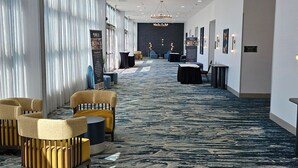 Un hall d’hôtel avec un tapis à motifs, des espaces aménagés pour s’asseoir et un lustre.