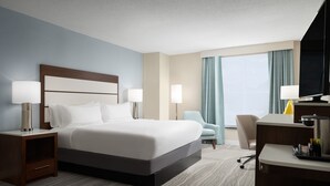 Une chambre d’hôtel comprenant un lit, des tables de chevet, un bureau, une chaise et un téléviseur.