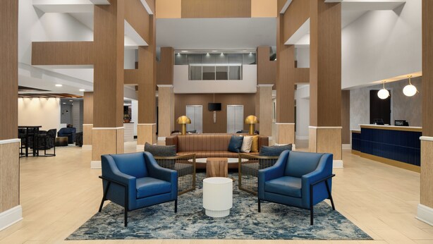 Un hall d’entrée spacieux avec un espace salon central, un comptoir d’accueil et un plafond haut doté de lucarnes.