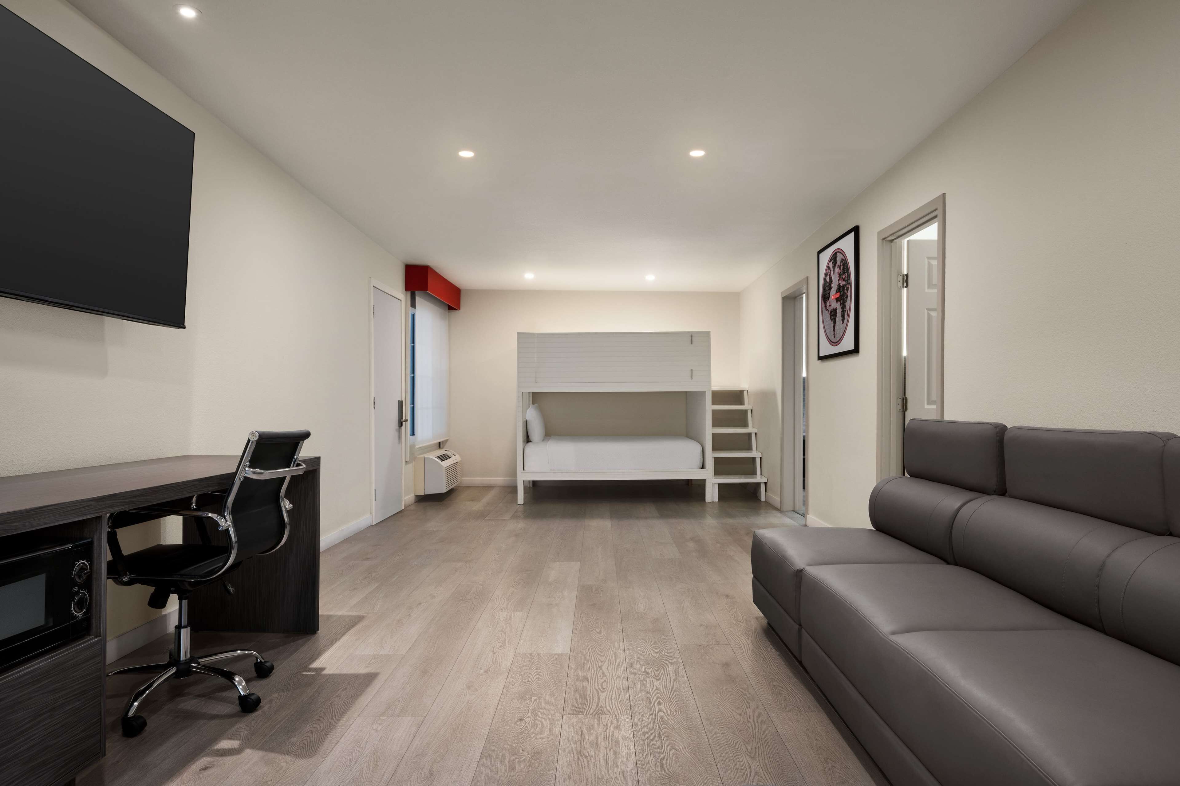 A modern bedroom with a bed, a desk, and a sofa.