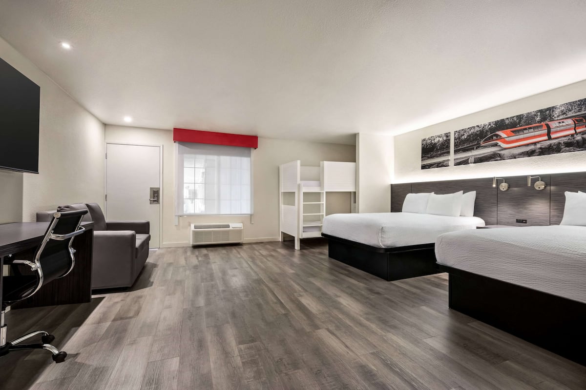 A modern hotel room with a large bed, a desk, a chair, and a wardrobe.