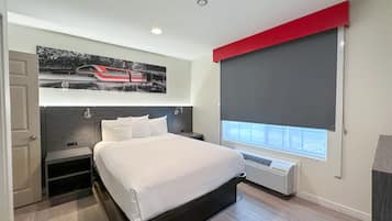 Una camera da letto moderna con un letto, una finestra con persiana, un termosifone e un'opera d'arte appesa al muro raffigurante un treno.